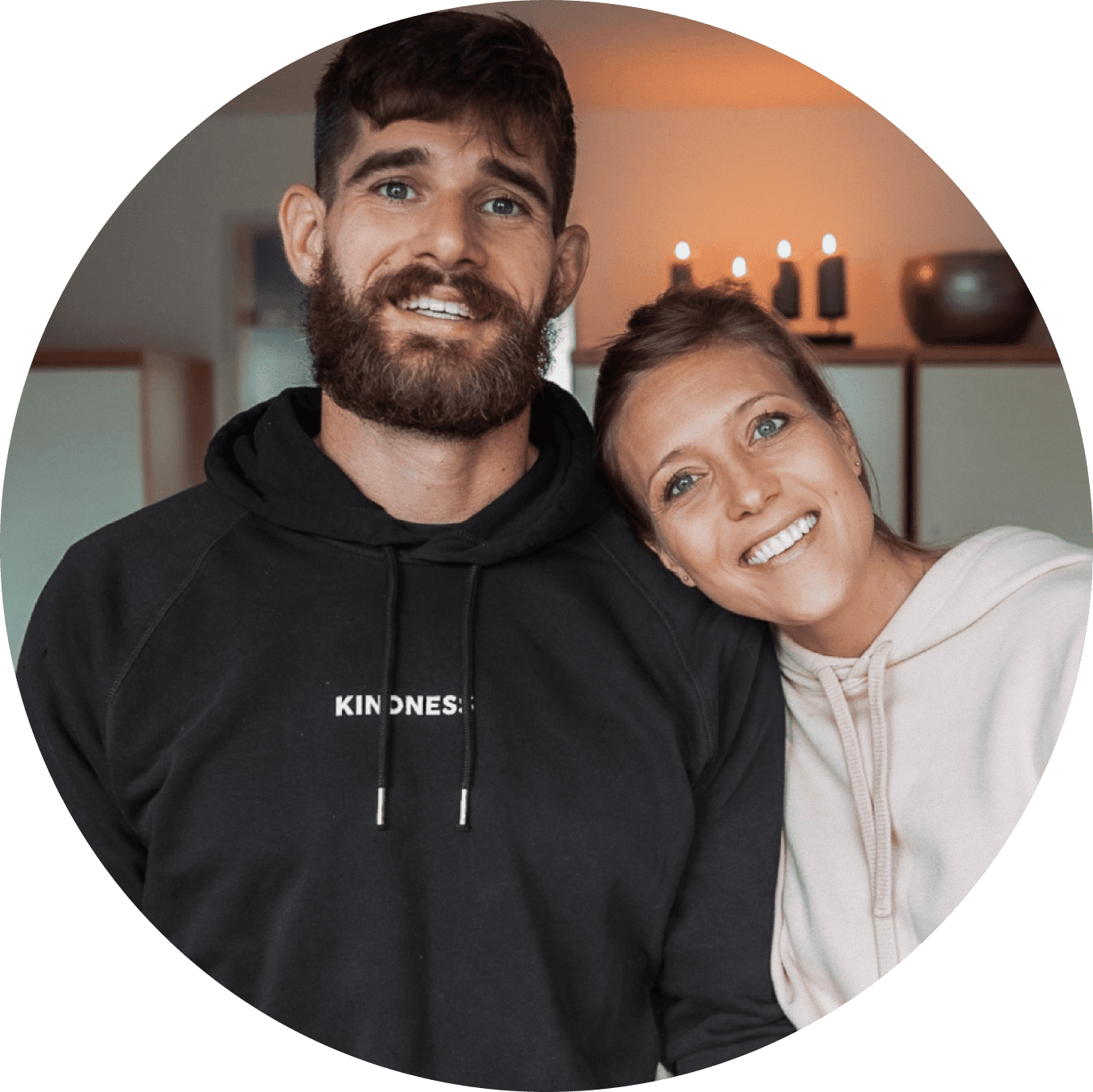 Bre and Flo smiling together towards the camera in a warm candlelit room.