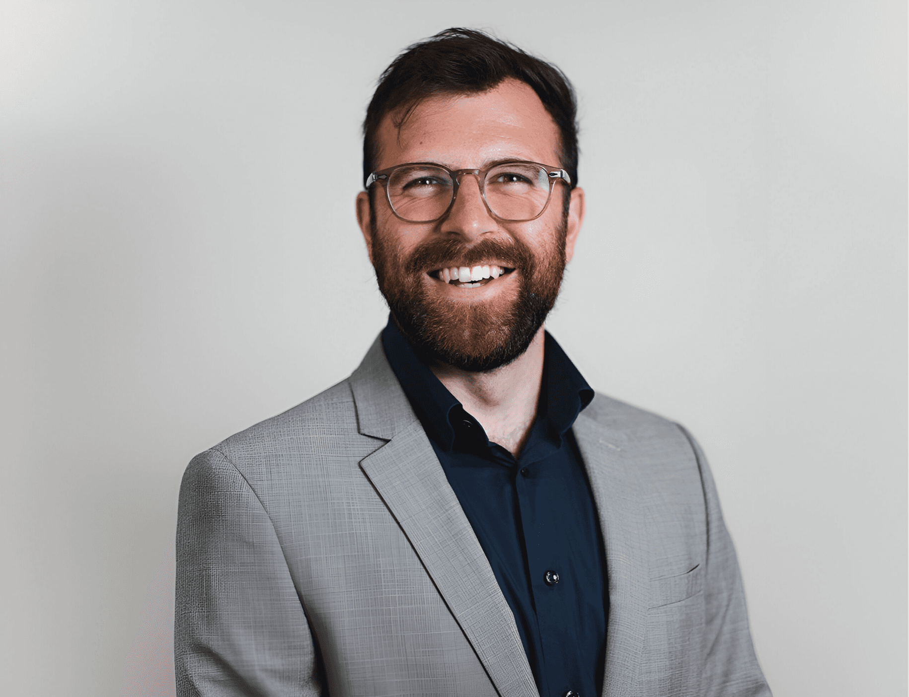 Person wearing a blue puffer jacket and red backpack standing in front of a light blue building on a city street.