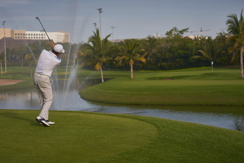 Couple standing on a balcony with binoculars in hand looking out over the ocean