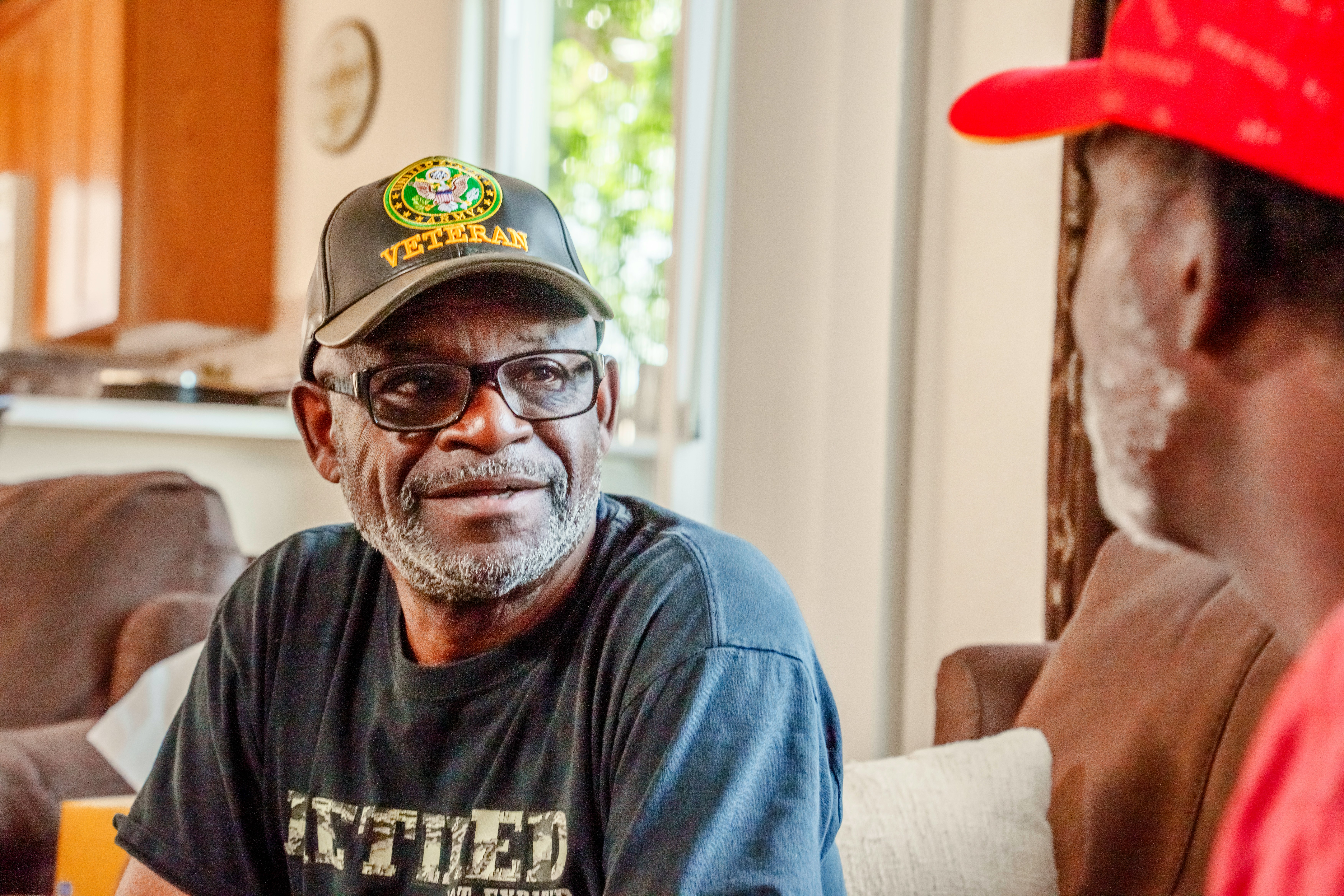 Two men talking, one wears a veteran hat.