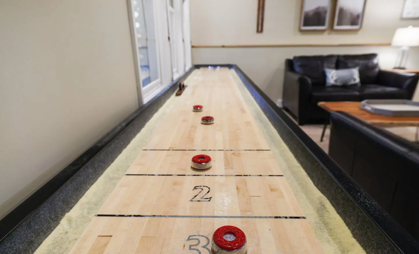 Long shuffleboard table with pucks in the lower game room at Mountainwoods Memories