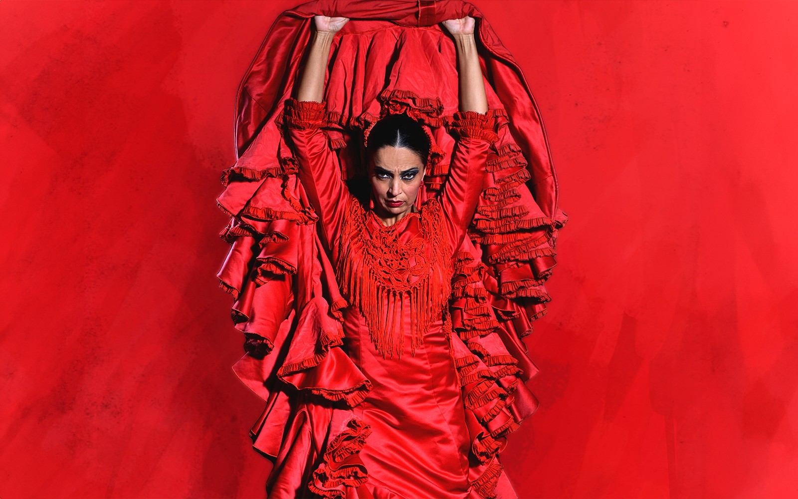Flamencodanser i rød kjole opptrer på Teatro Flamenco Granada.