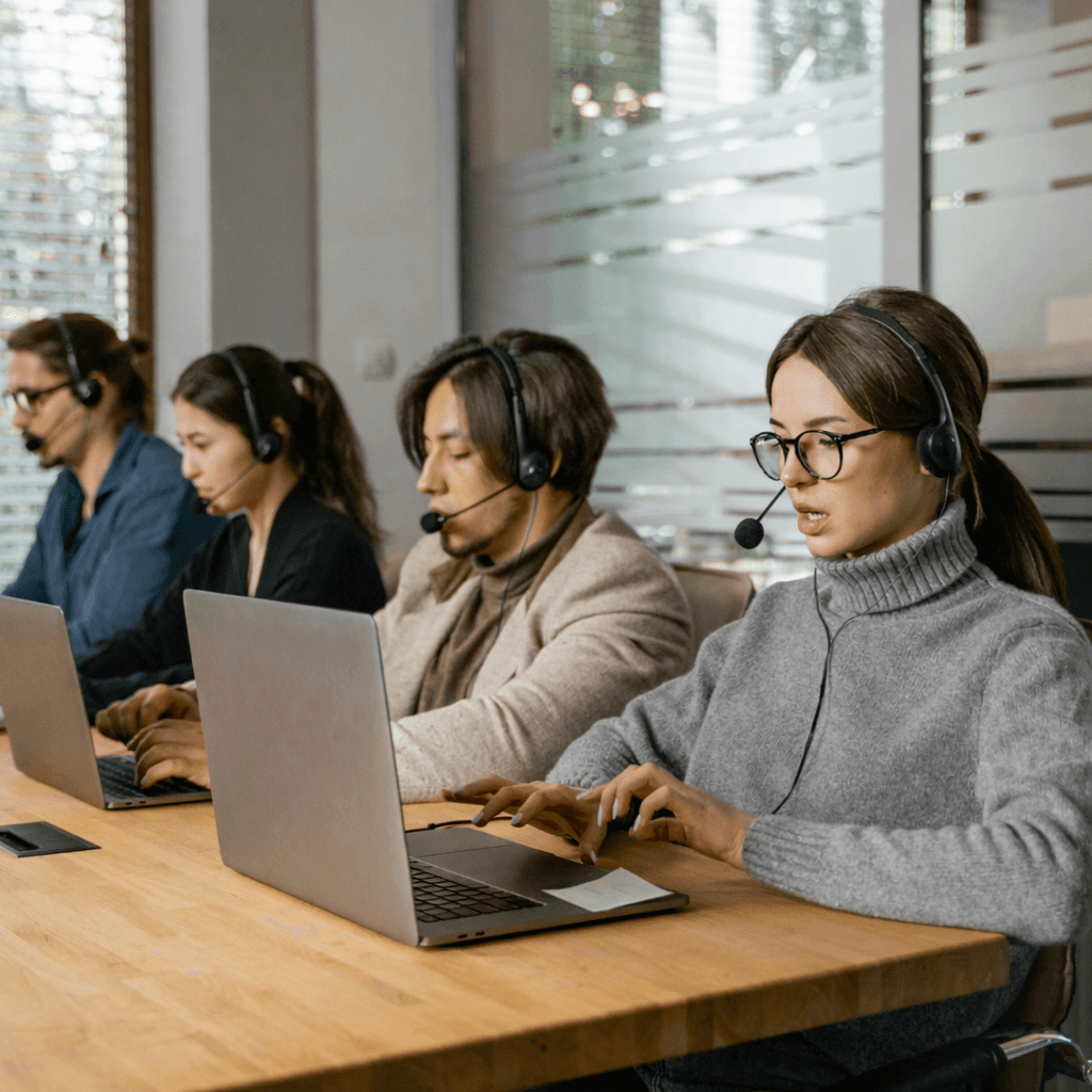 Small business team using laptops and headsets for affordable communications, customer engagement, and unified business phone systems for call handling.