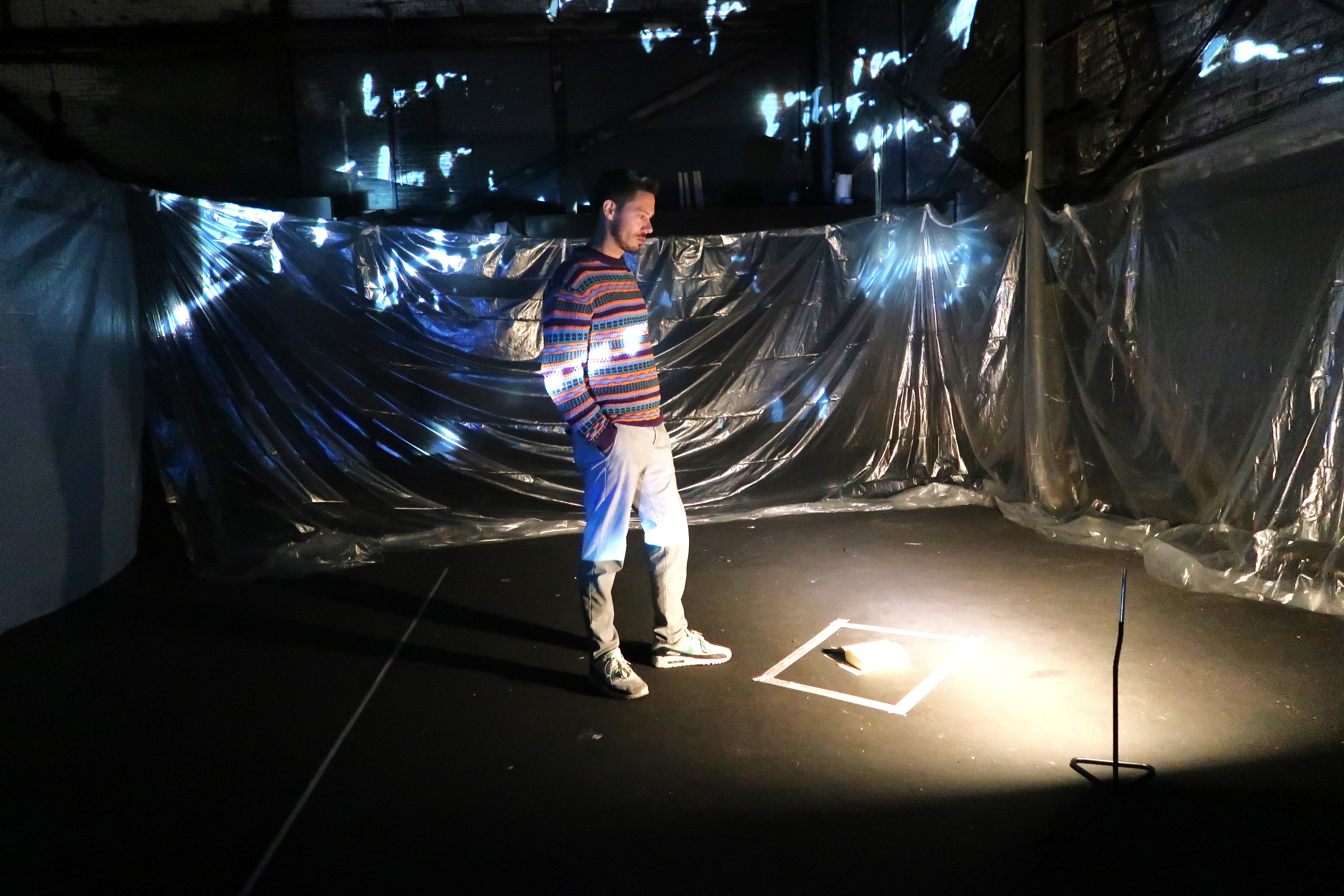 A smiling woman with her arms crossed, standing against a dark green background. She has long, dark hair.