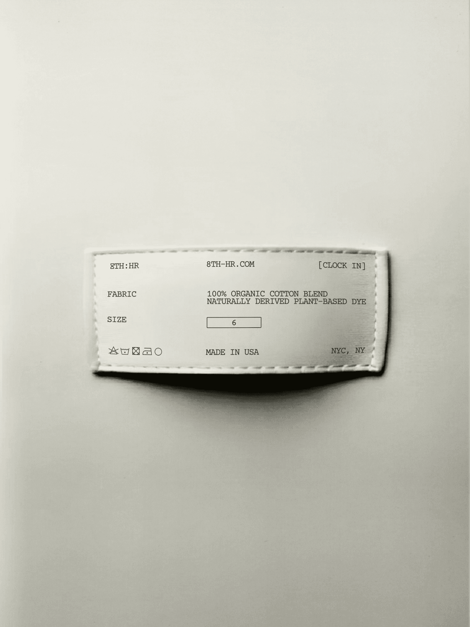 A white clothing label laying on a white background.