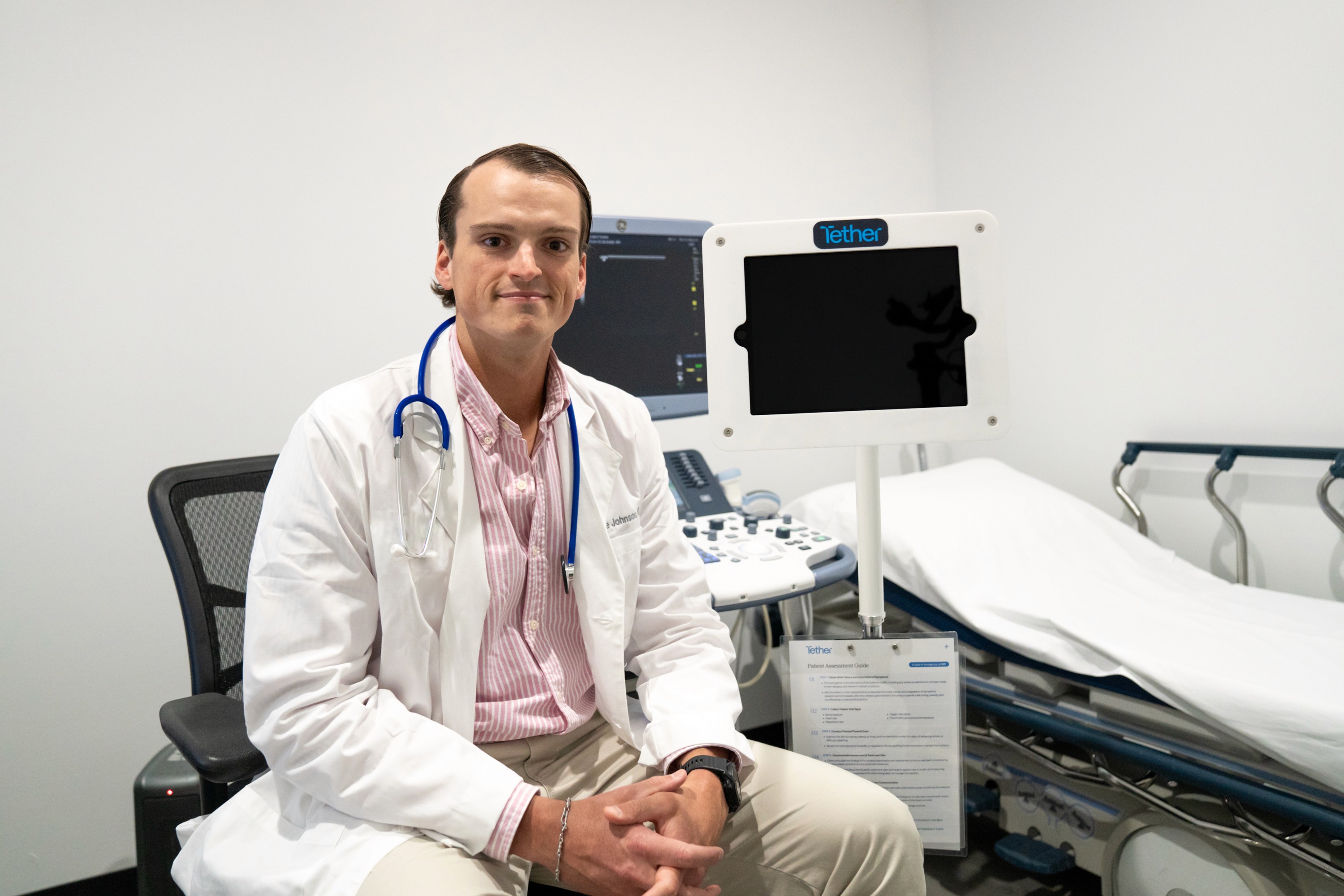 Clinician seated beside a Tether Supervision mobile contrast unit in an outpatient imaging exam room, demonstrating always-available virtual direct supervision for contrast-enhanced CT and MRI procedures through a secure, HIPAA-compliant platform.