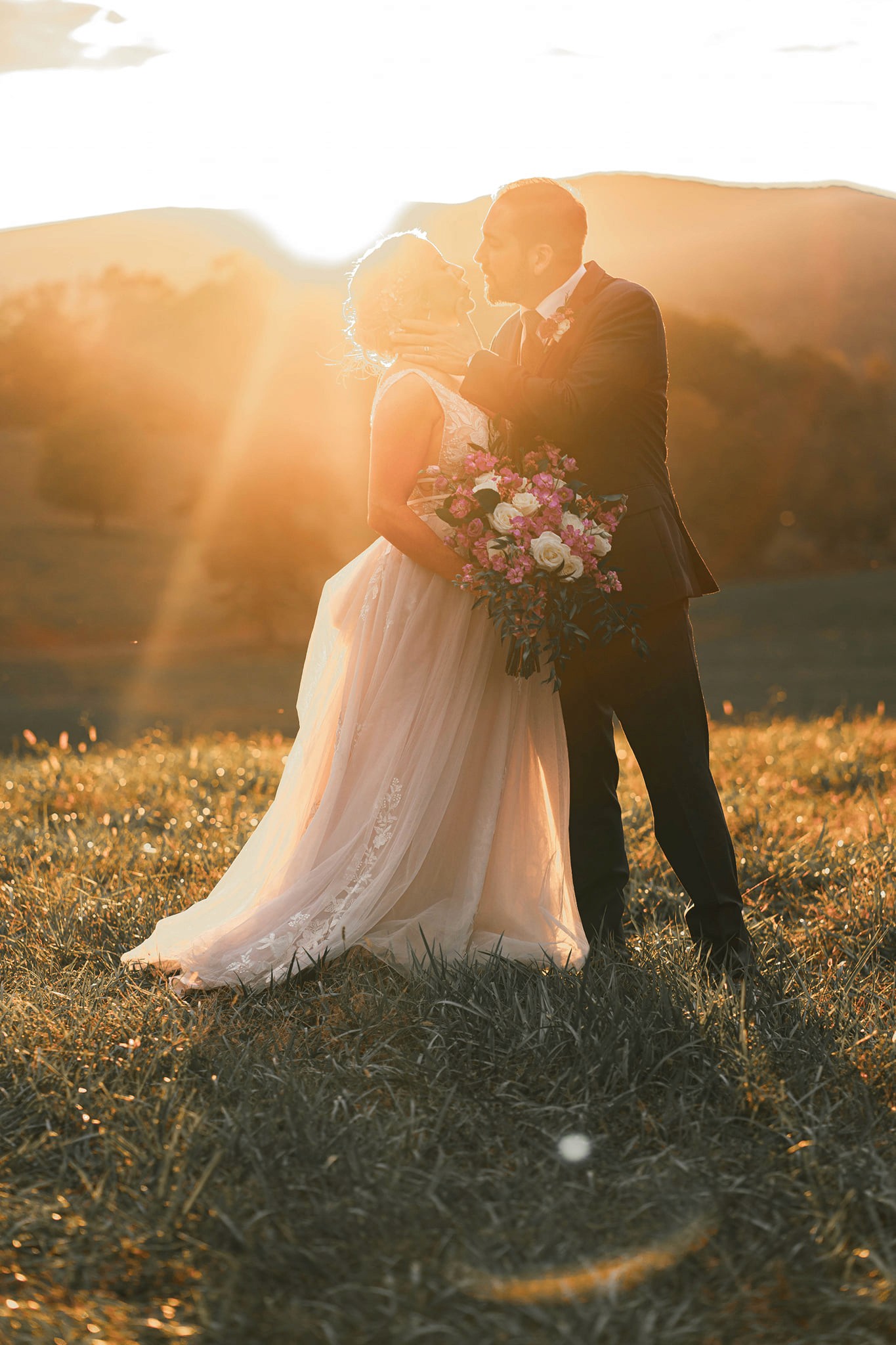 A couple stands outdoors at sunset.