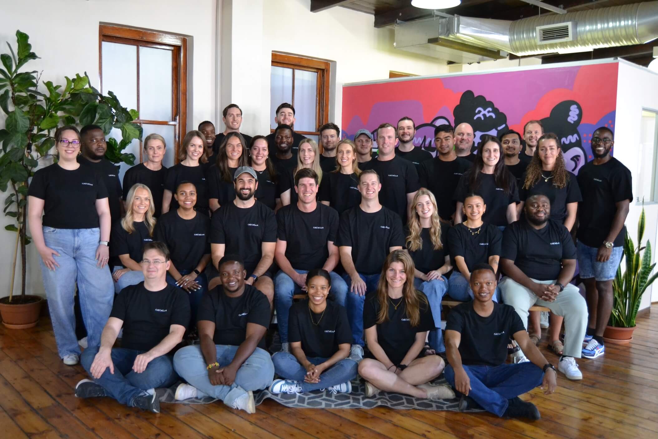 Team photograph of the Cue staff, a mix of men and women smiling at the camera.