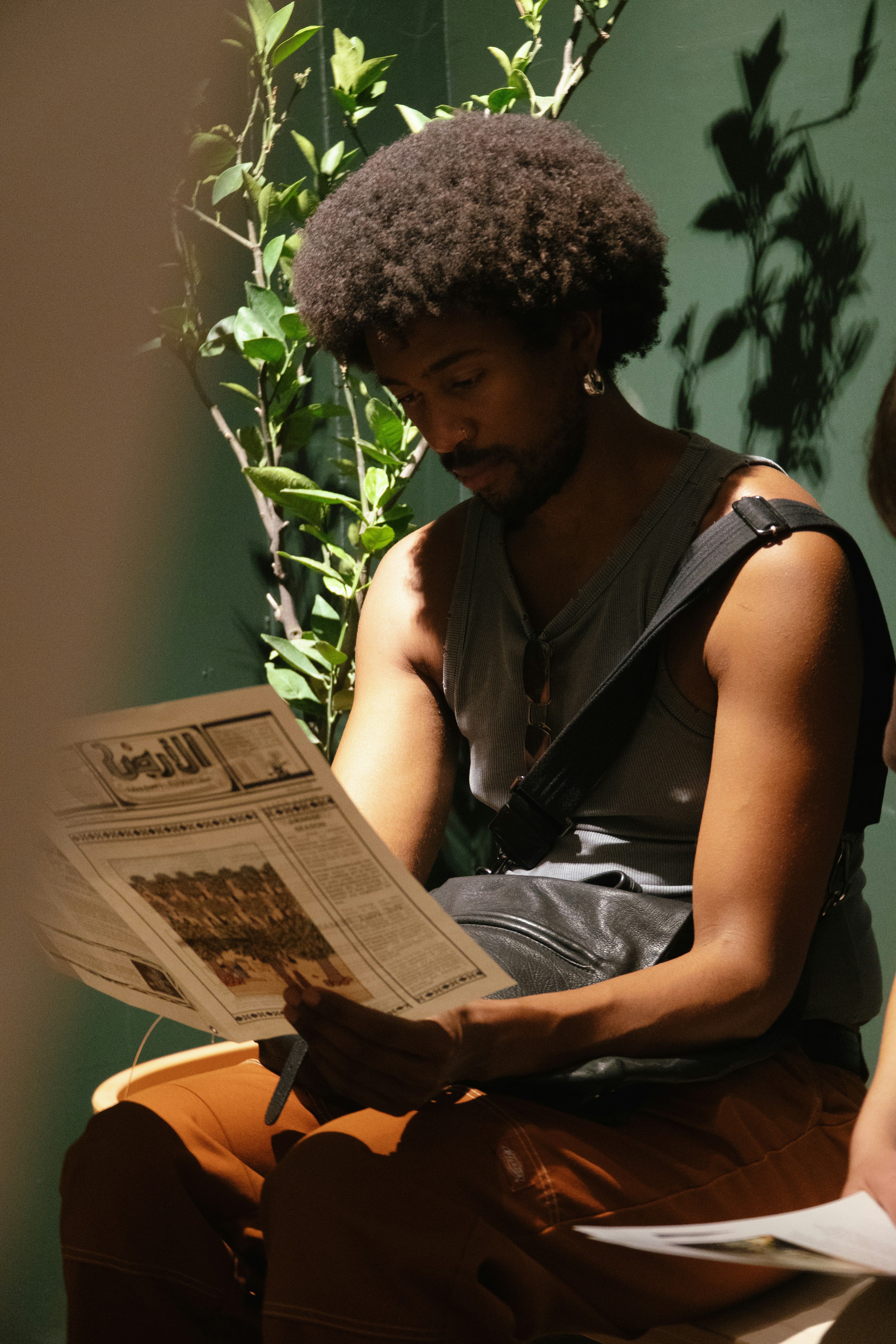 Man with afro reading a newspaper indoors