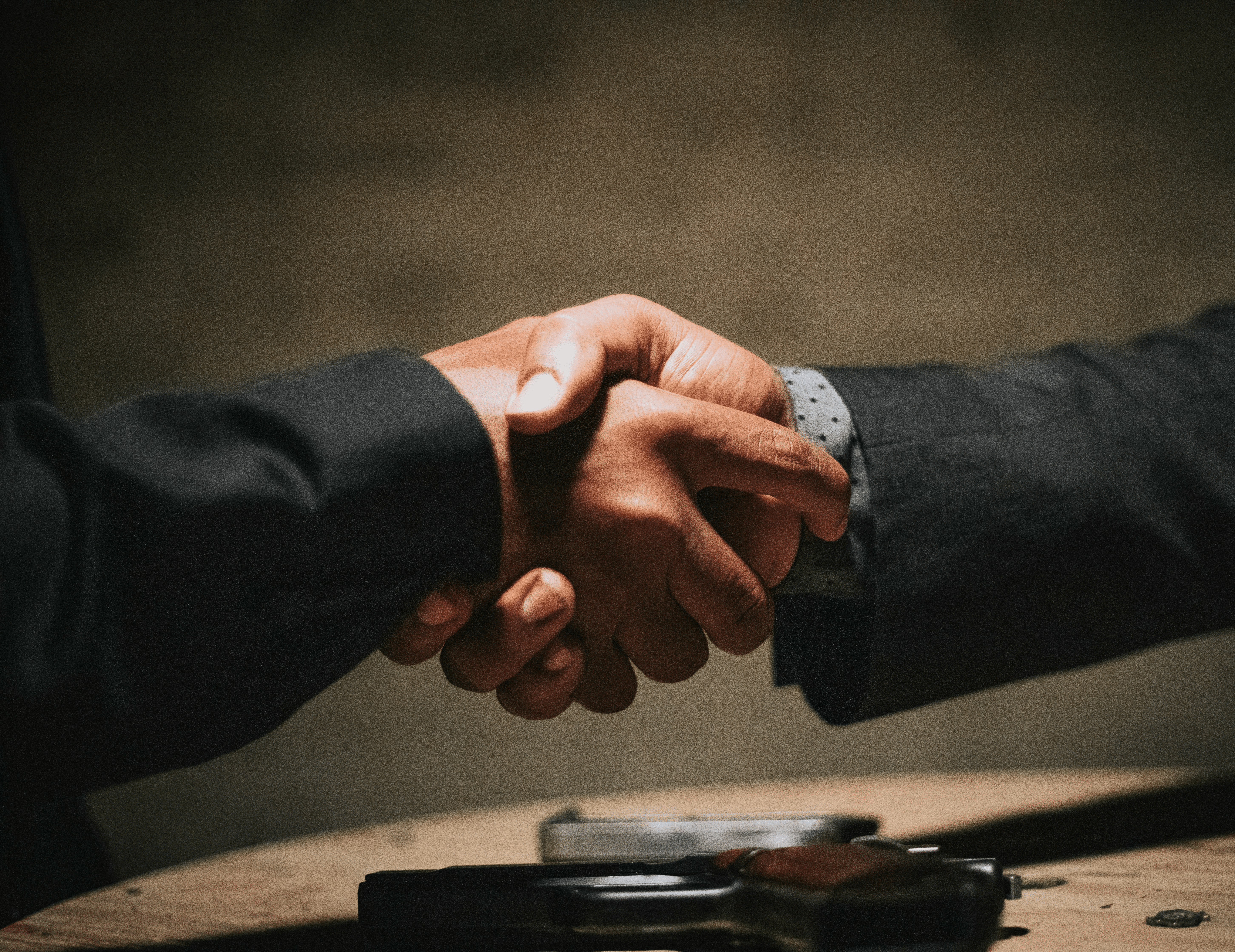 two people shaking hands over a wooden table