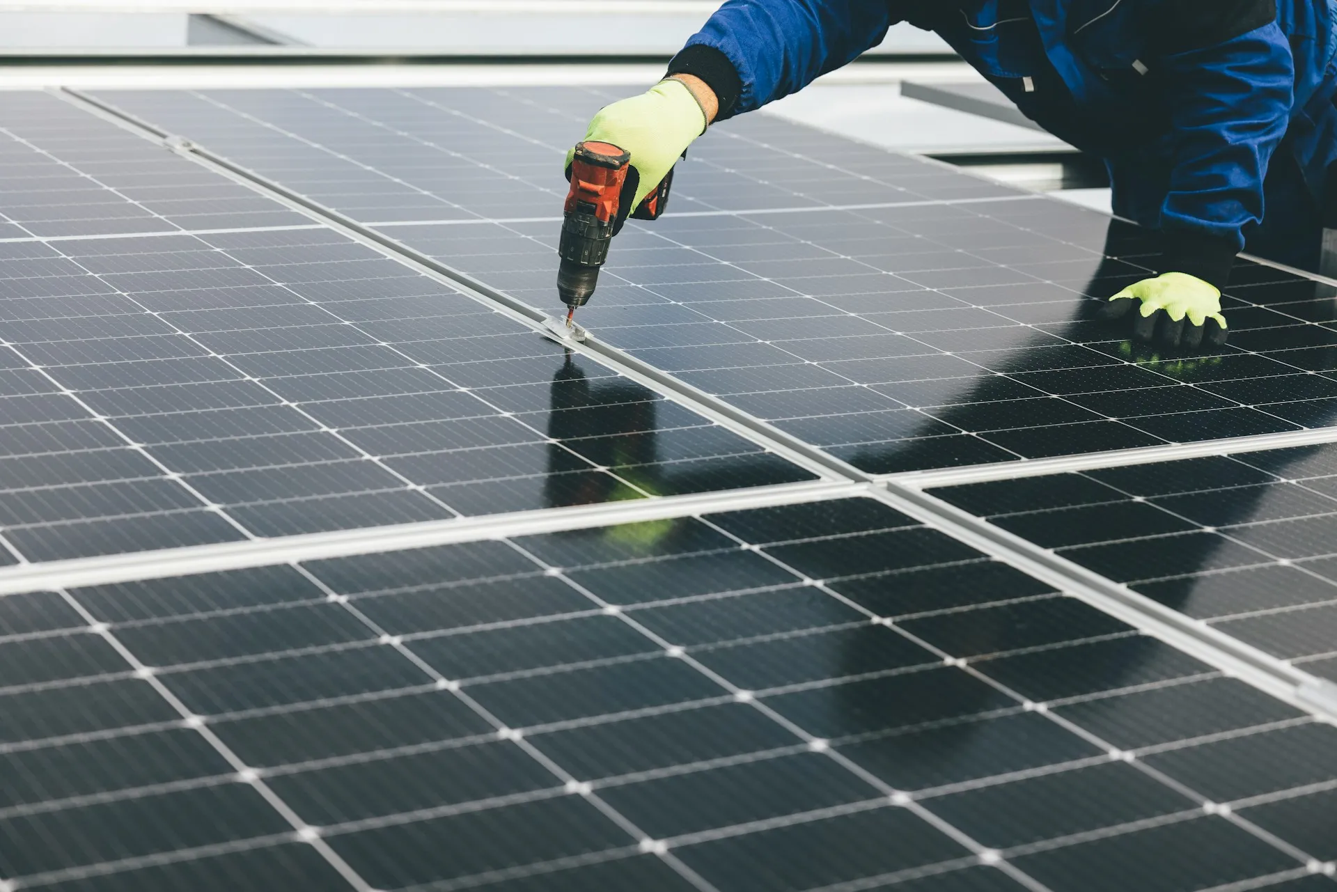 Auf einem flachen Betondach ist eine Vielzahl blauer Solarmodule installiert, die aus Sonnenlicht erneuerbare Energie erzeugen.