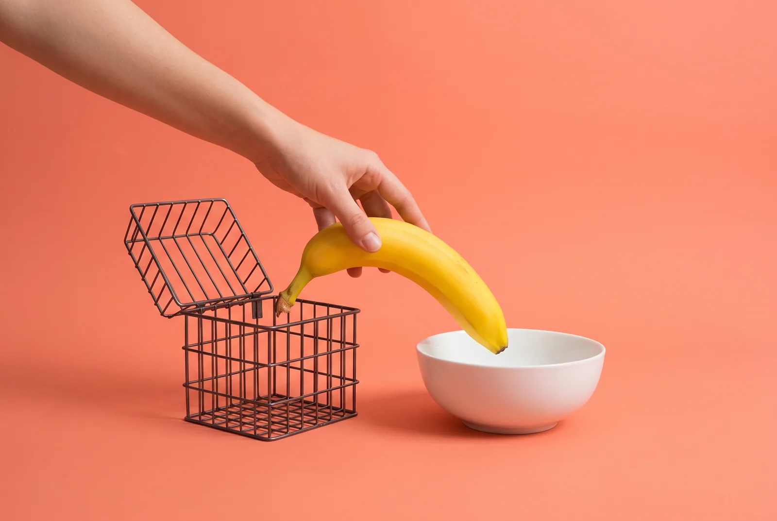 A hand moving a banana from a small cage into an open fruit bowl, switching from Covenant Eyes