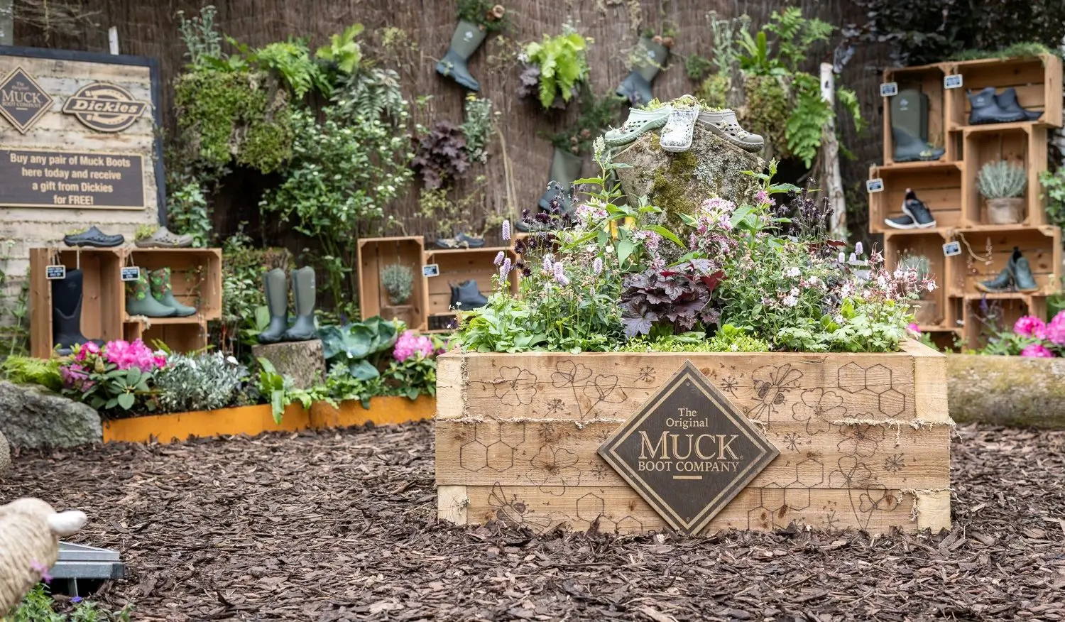 A vibrant garden featuring colorful flowers, plants, and stone planters arranged in a neat outdoor space.