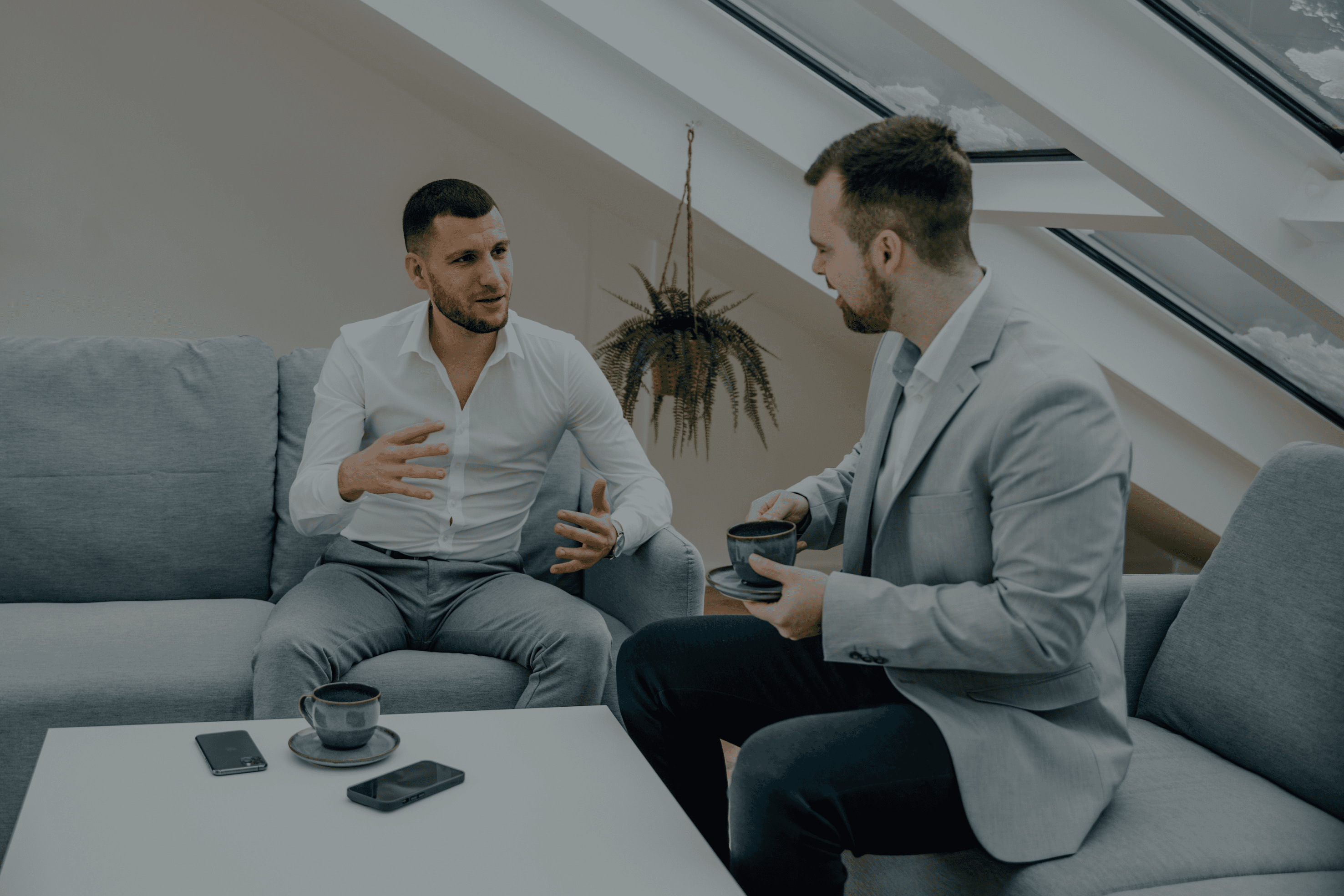 two men sitting on a couch talking to each other