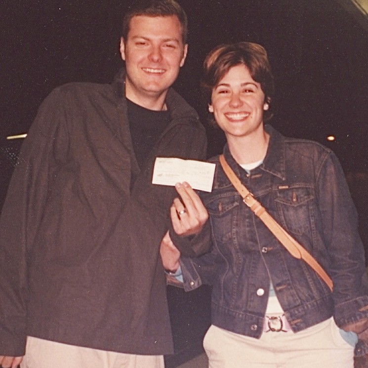 Young Kyra and Rob Hartnett smiling happily while holding up a check.