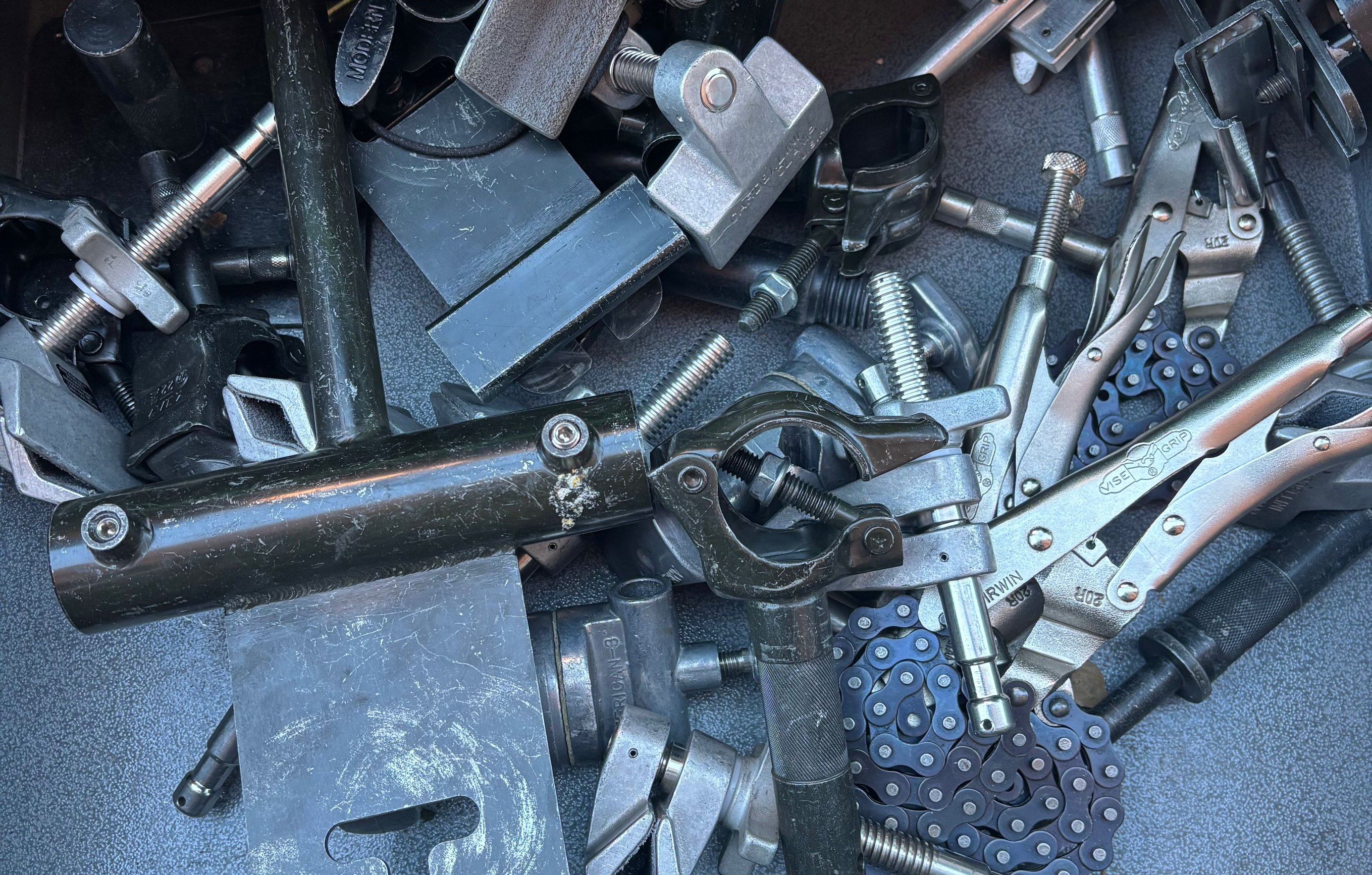 An open grip-cart drawer full of mounting hardware - cardellinis, mafer clamps, pipe clamps, baby pins, vise grips and safety chain.