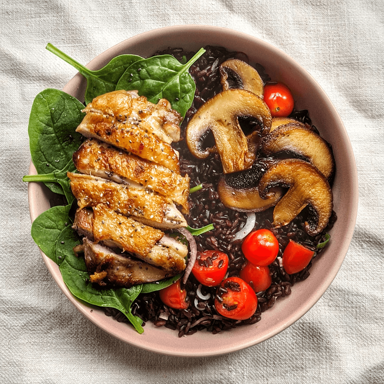 Bol de riz noir, poulet, champignons et tomates.