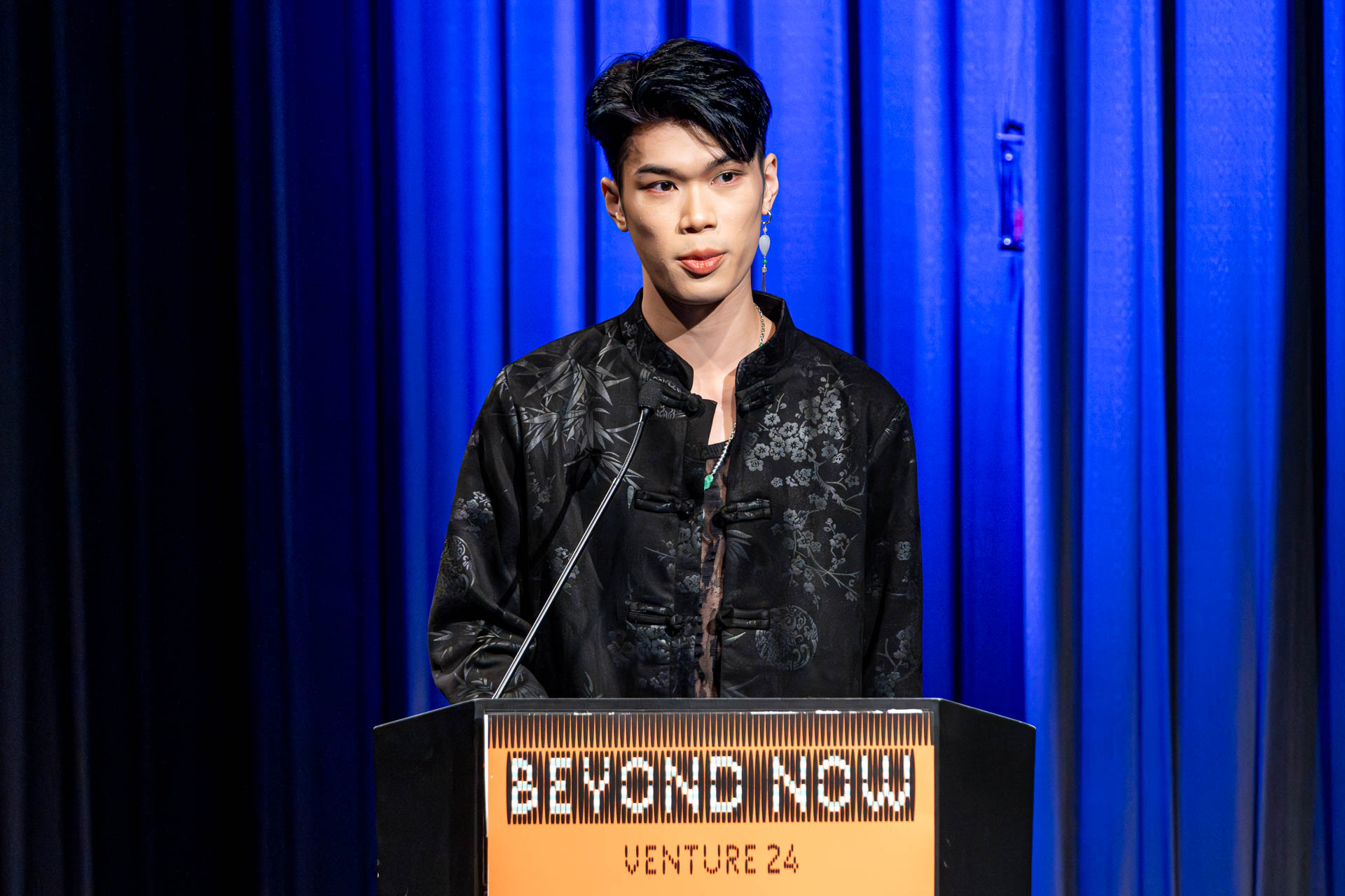 a student at a podium presenting a project in a Theatre