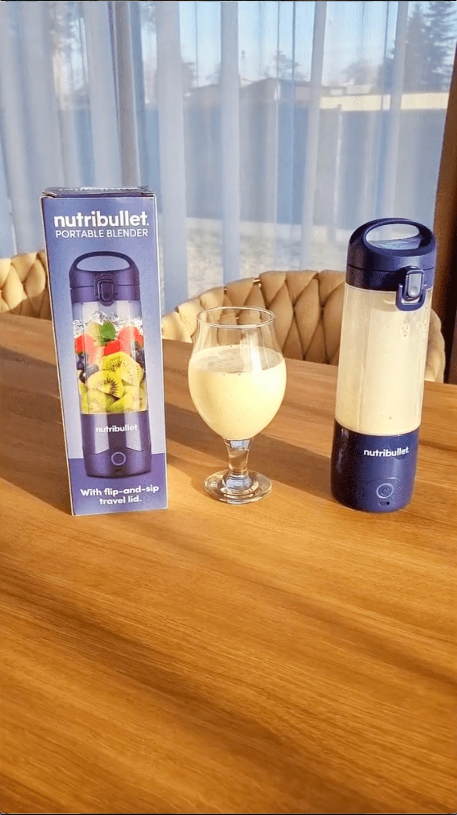 Nutribullet portable blender with a glass of banana protein smoothie drink on top of a wooden table