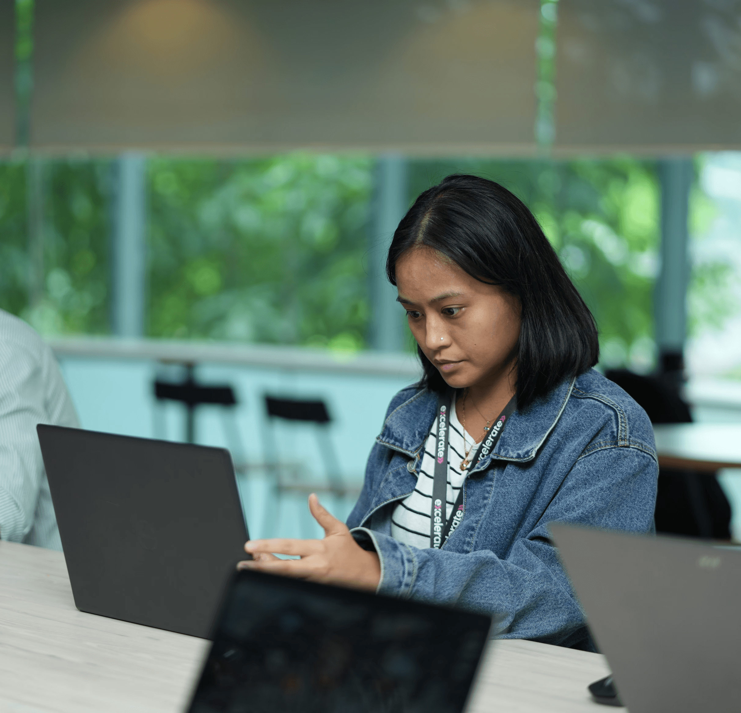 A woman at a table using a laptop, symbolizing the integration of AI in data-driven business strategies.