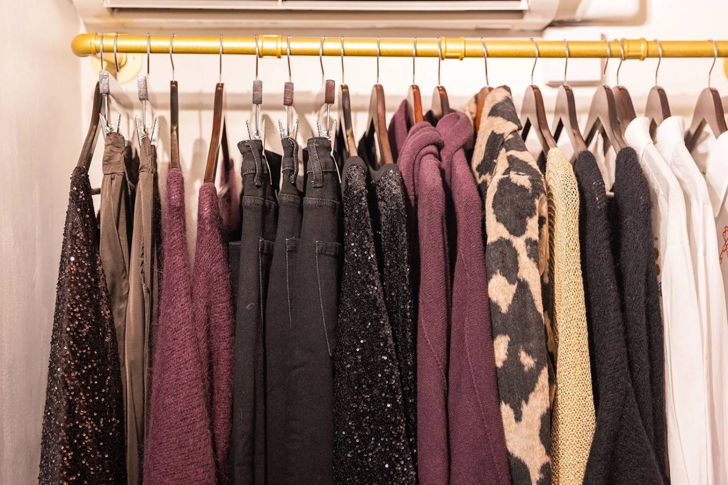 A curated autumn wardrobe rail featuring rich textures, deep berry tones, sequins, knits, animal print and cosy neutrals, showcasing how varied fabrics add depth and luxury to a seasonal capsule