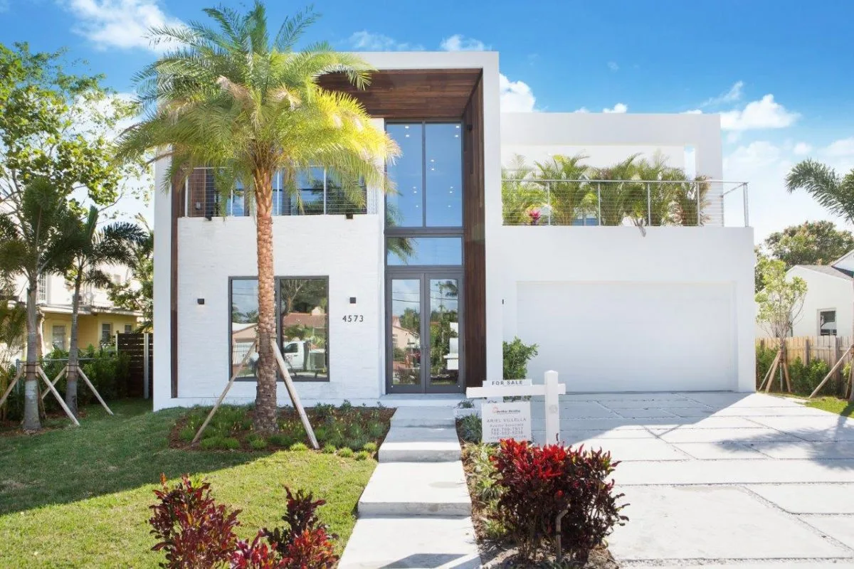 Front facade of modern two-story home with floor-to-ceiling glass and wood cladding on Prairie Avenue Miami Beach