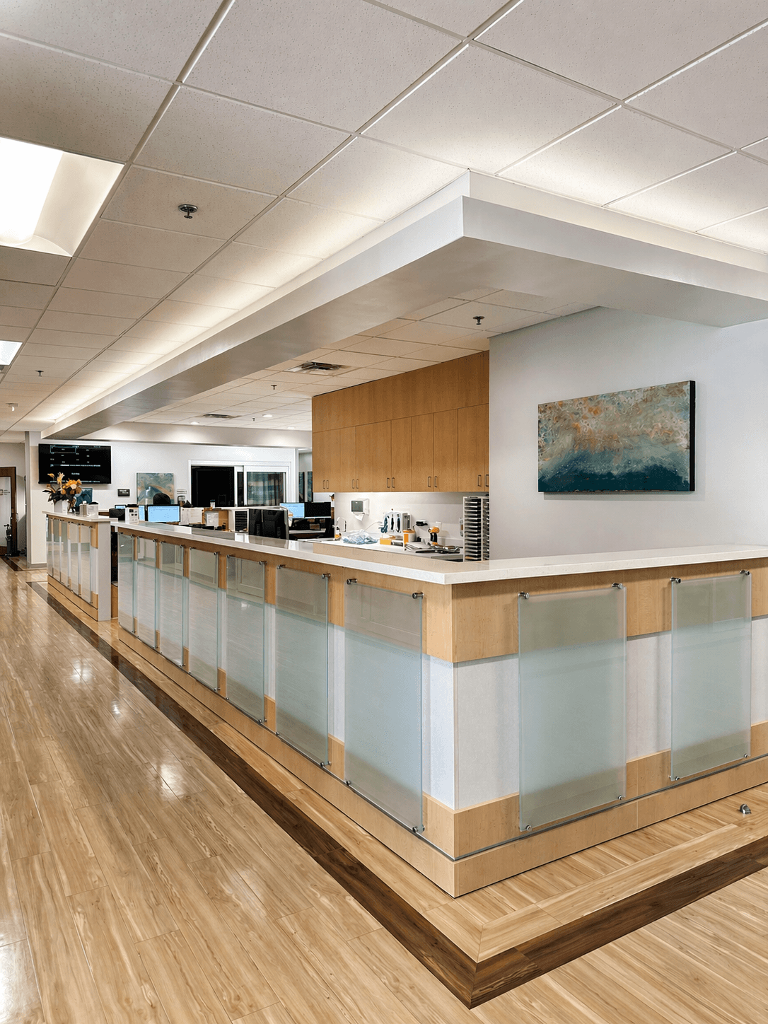 Custom wood and glass reception desk with built-in cabinetry for Austin Emergency Center by QW Kitchen & Bath