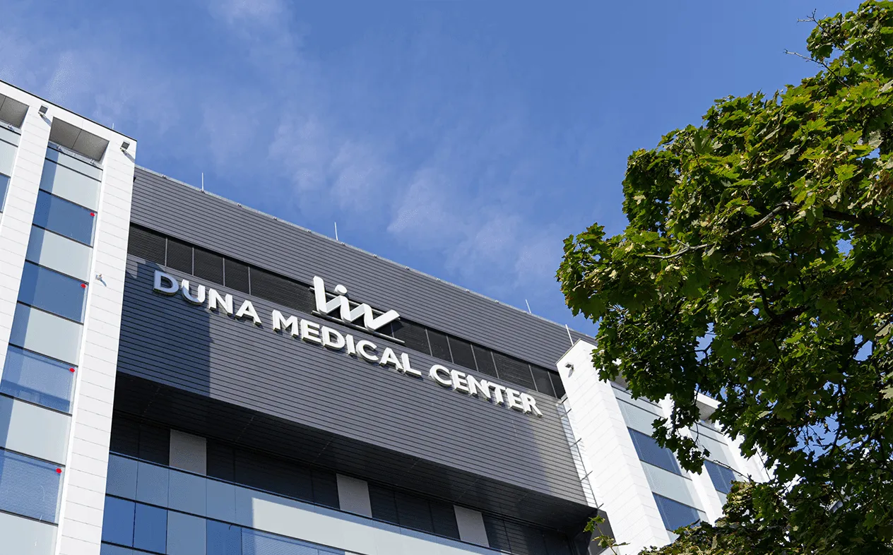  image of Imperial Dental's modern treatment room featuring blue dental equipment, a monitor with the clinic’s logo, and natural light from large windows overlooking a park.