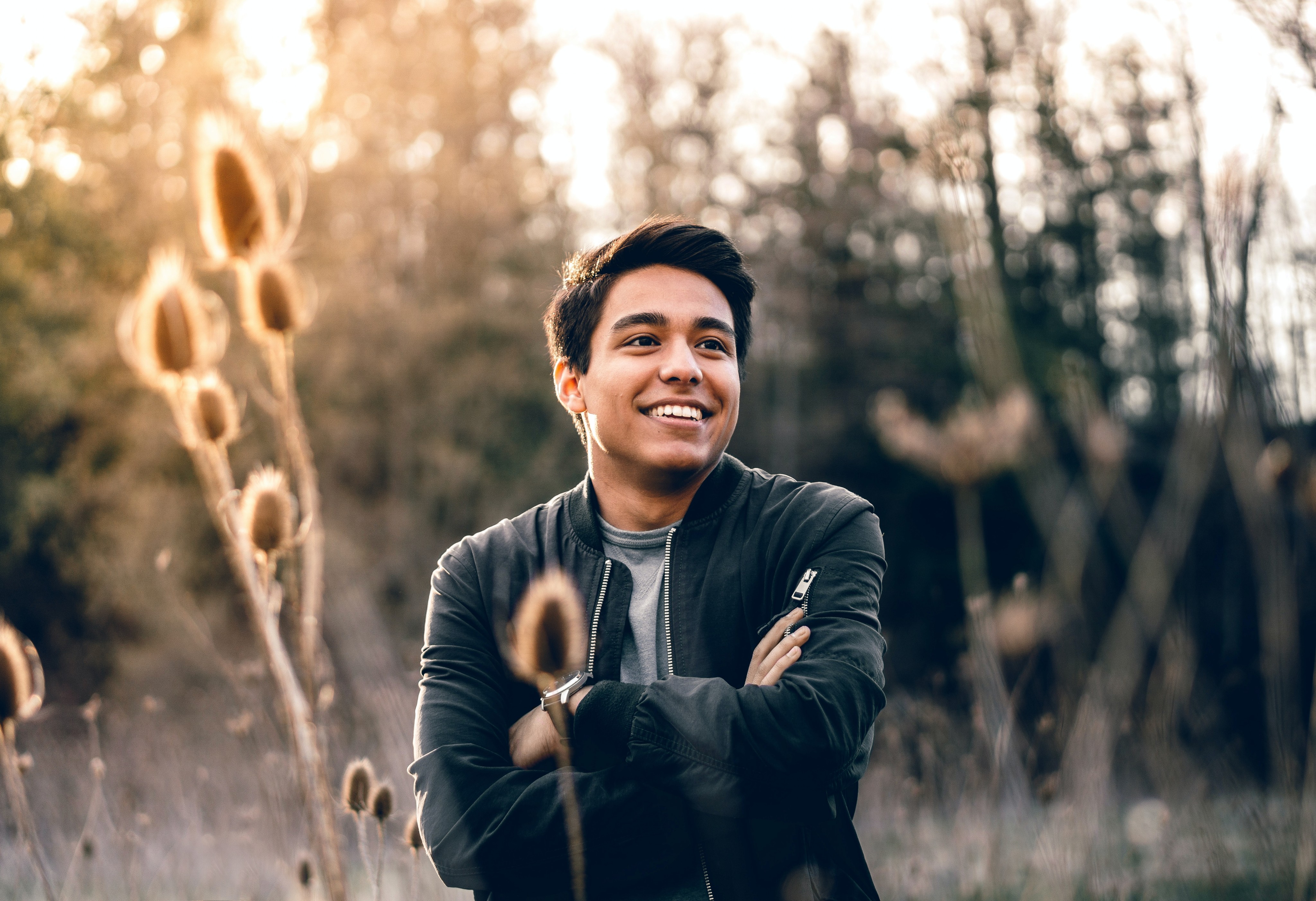 A cinematic portrait shot of a man wearing a black jacket in a field