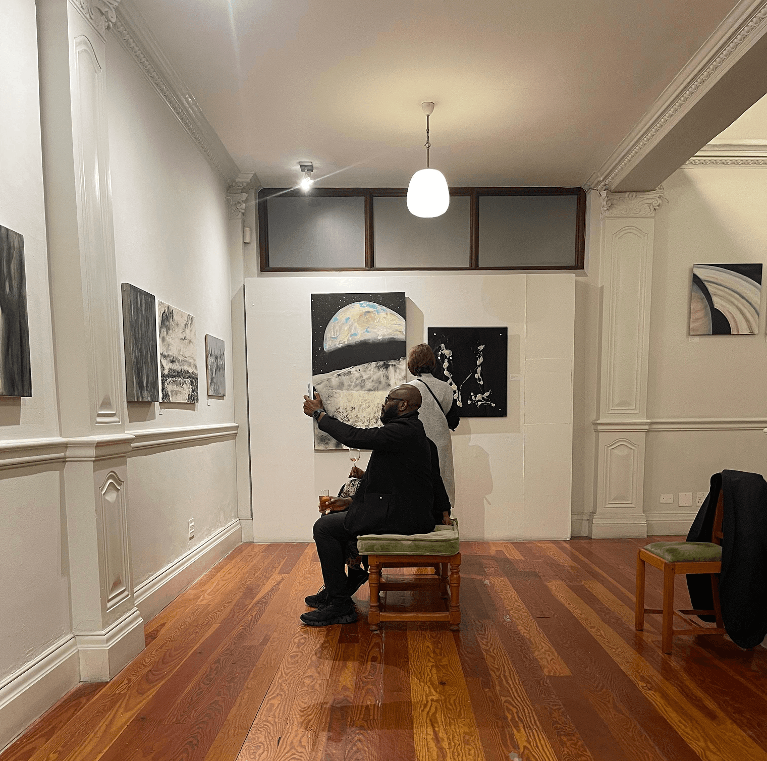 two people facing to the right, standing in front of two arworks