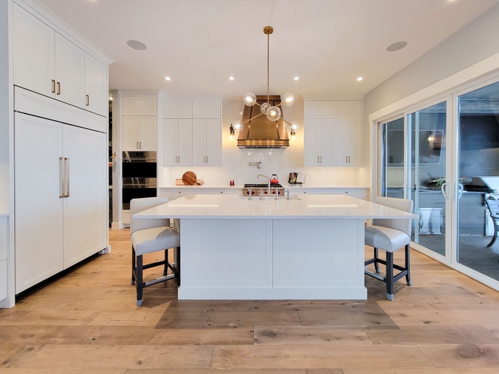 Image of Modern kitchen with white cabinets, island seating, and hardwood floors designed by KHD Homes.