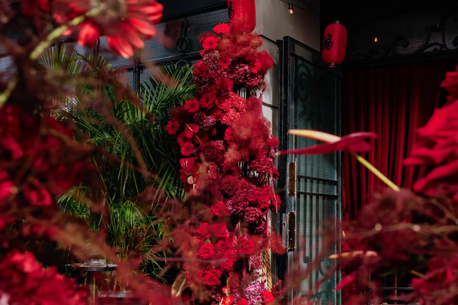 Estructura floral orgánica de rosas y gerberas rojas en entrada de Tequila Club.