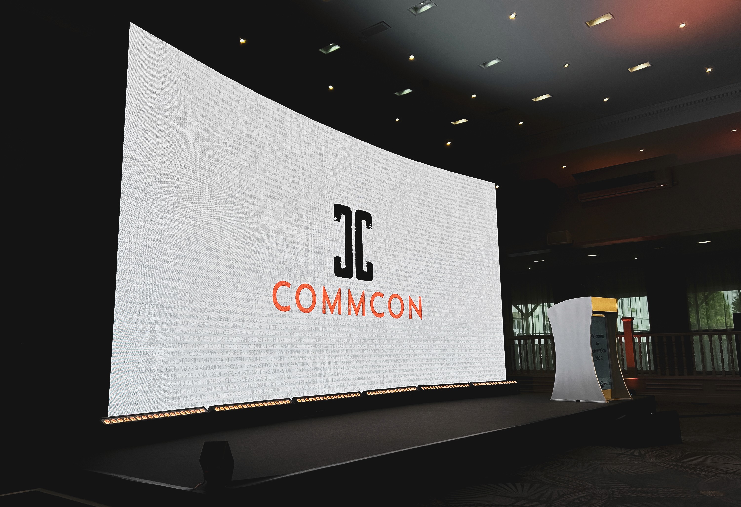 Curved CommCon 2023 LED wall and digital lectern on the main conference stage