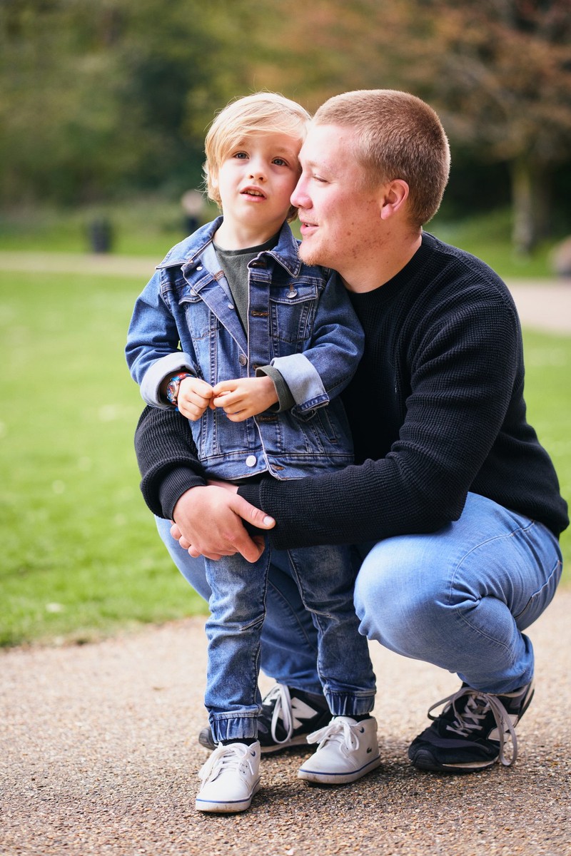 Dad crouching to hug his young son on a park path