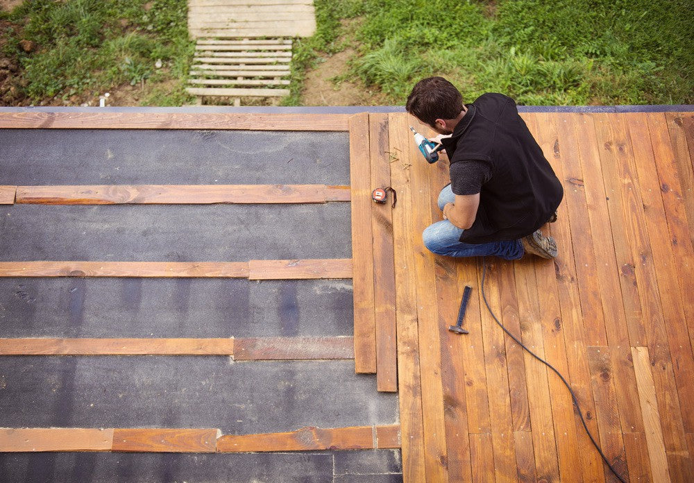 師傅於戶外地台安裝實木地板材料，展示專業鋪設防腐木工程，提供優質裝修地板方案。