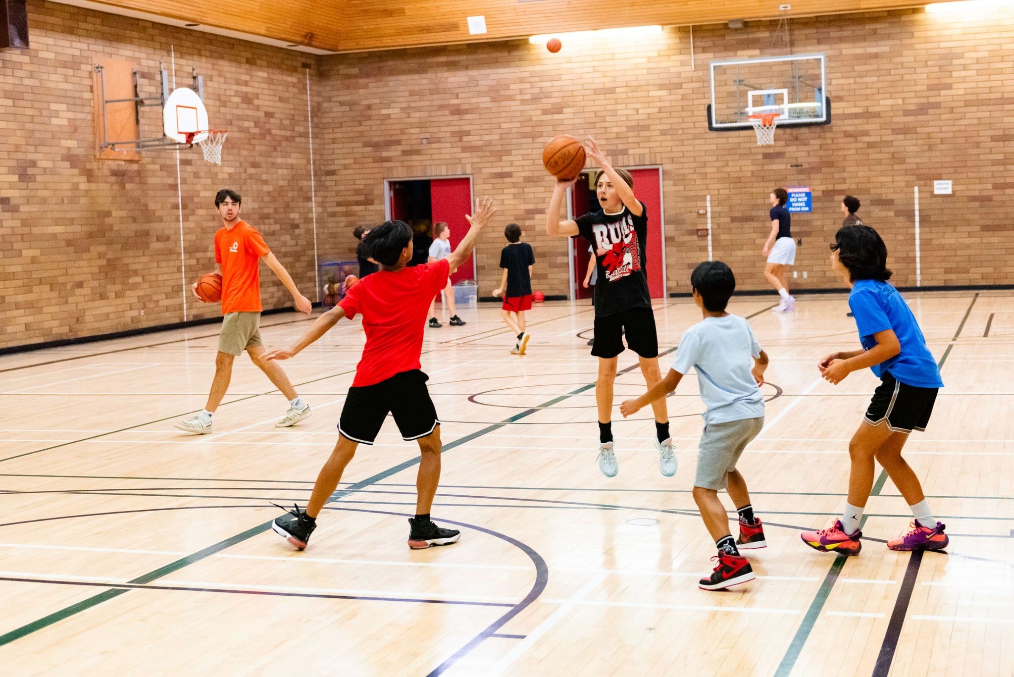 Youth basketball players on an indoor court at a parks and recreation facility managed with TeamLinkt and Amilia