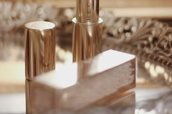 A beige nude lipstick bullet photographed close up against a carved wooden background