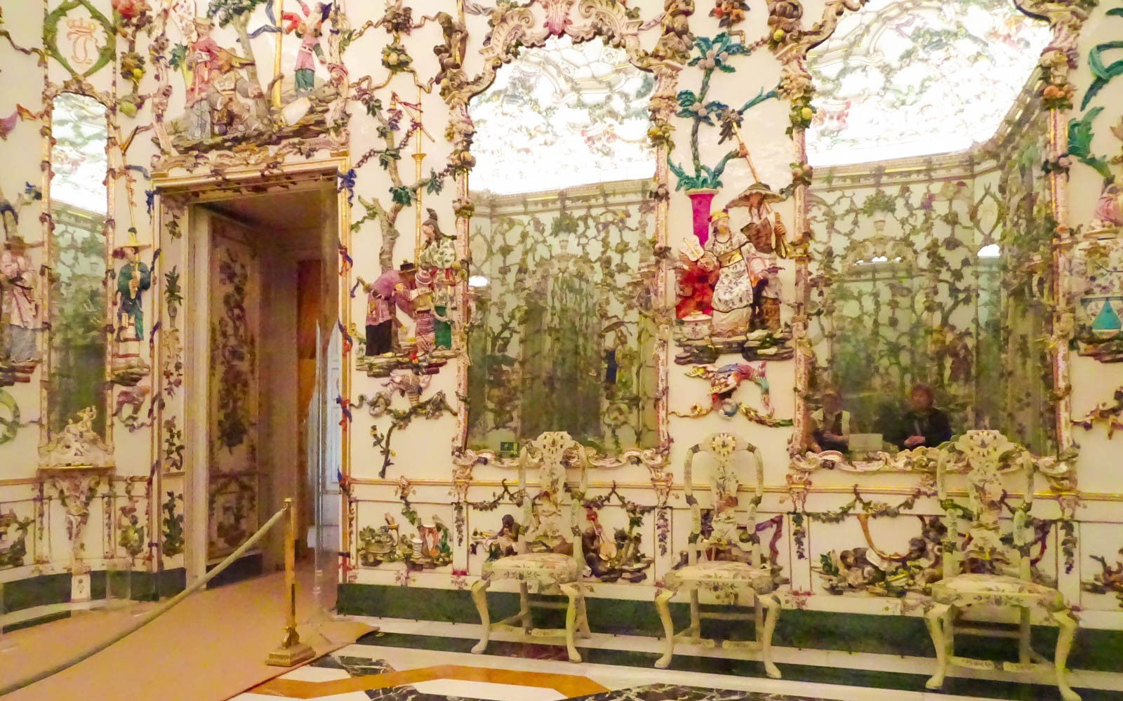 Ornate interior of the Royal Palace of Aranjuez with intricate wall decorations and mirrors.
