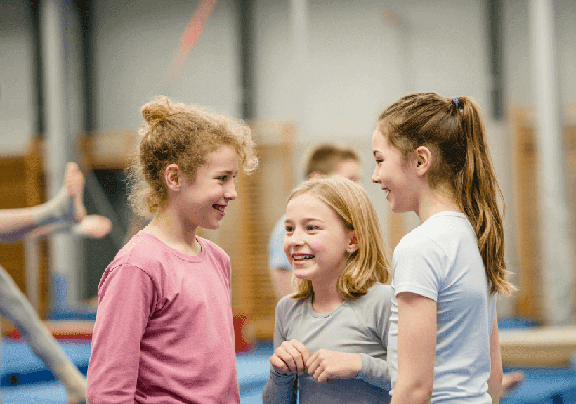 Trójka dziewczynek rozmawiające ze sobą na sali gimnastycznej