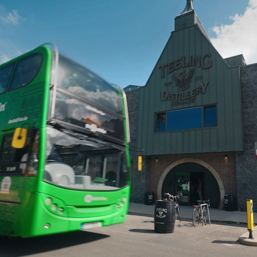 Green bus driving in front of whiskey distillery