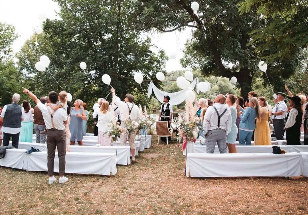 Ein glückliches Brautpaar und eine Freundin posieren für ein Hochzeitsfoto mit "Together"-Dekoration.