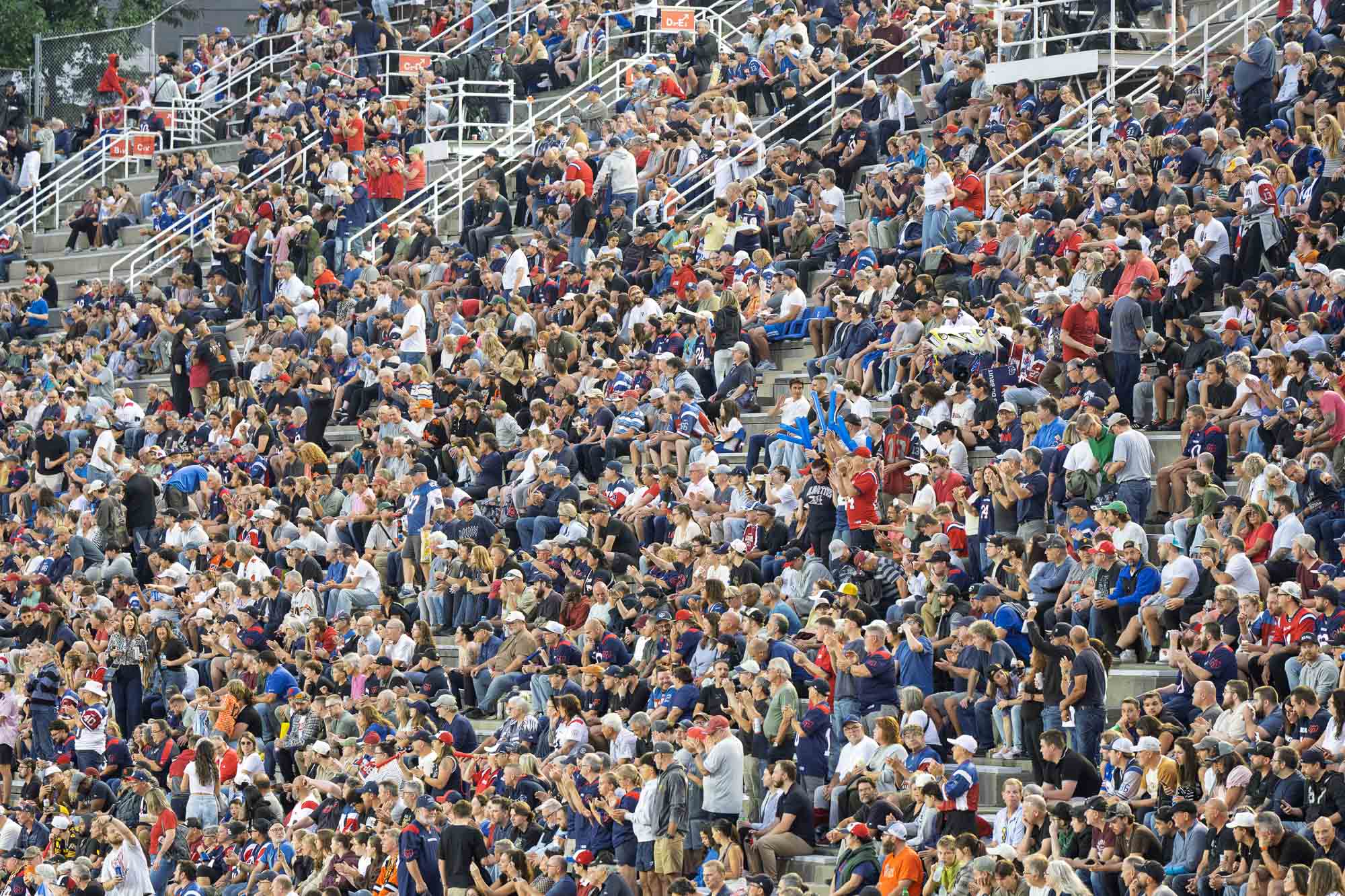 05_septembre_2026Quebec_20266784.jpg — Mât d’éclairage allumé au-dessus d’une tribune du stade Percival-Molson au crépuscule, quatre fanions aux couleurs des Alouettes claquant au vent.