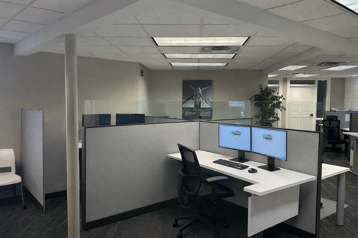 Man with a beard in a dark button-up shirt, smiling while writing in a notebook.