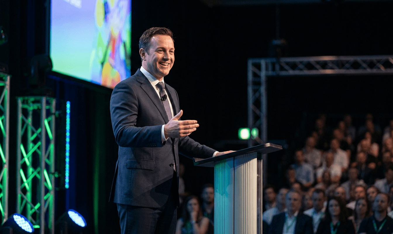 Young man in asks a question into a conference mic.