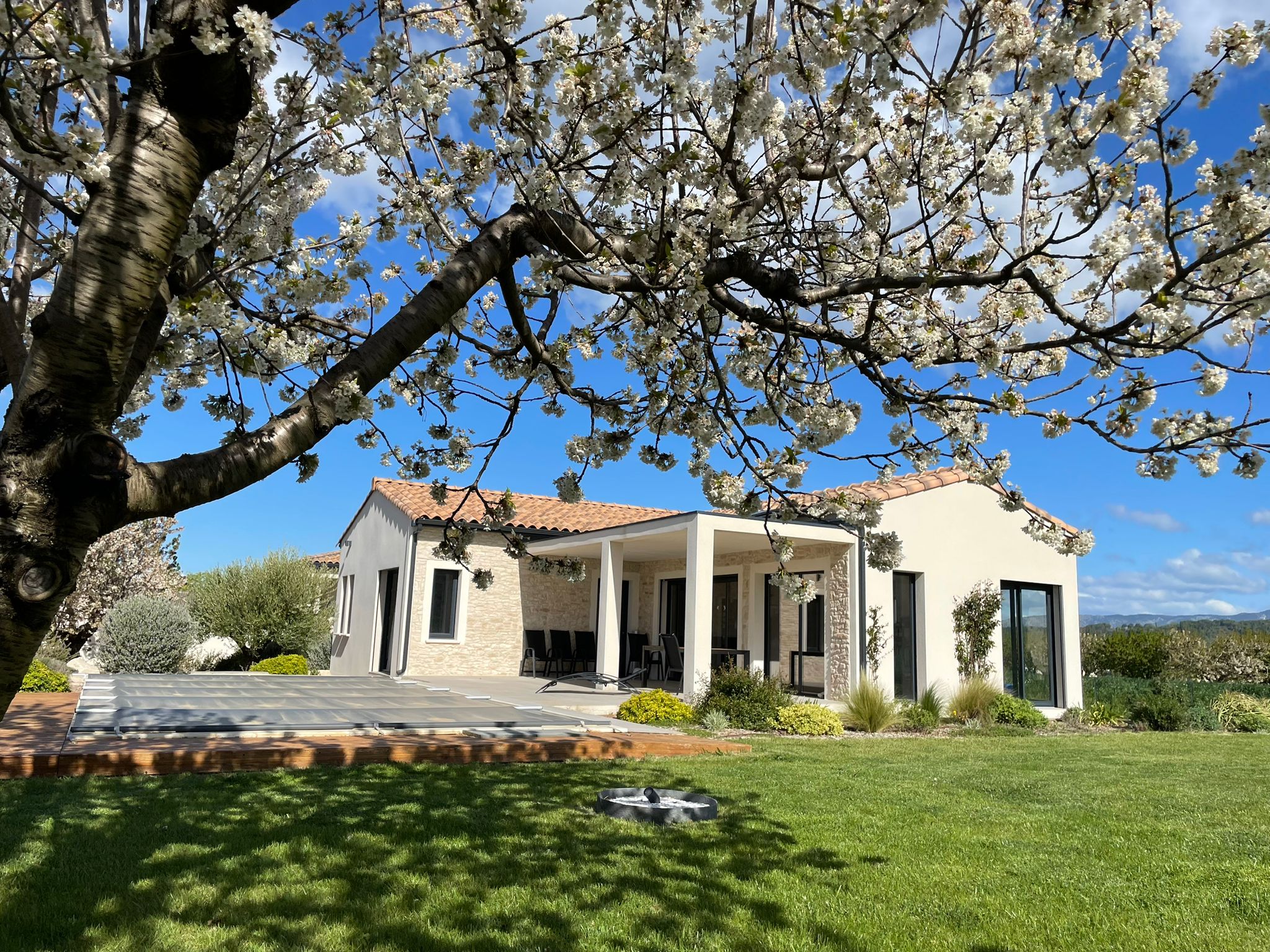 Belle maison de campagne sous un cerisier en fleurs. Vue extérieure, architecture et jardin.
