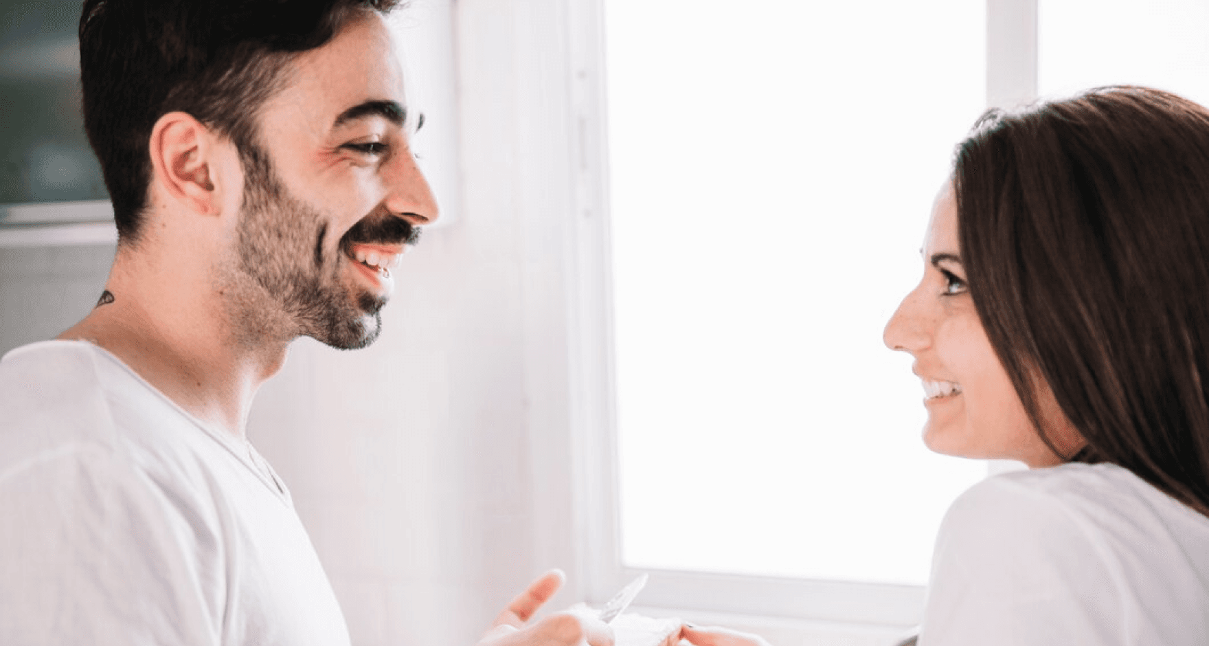 A couple smiling and looking at each other, engaging in a conversation about dental health.