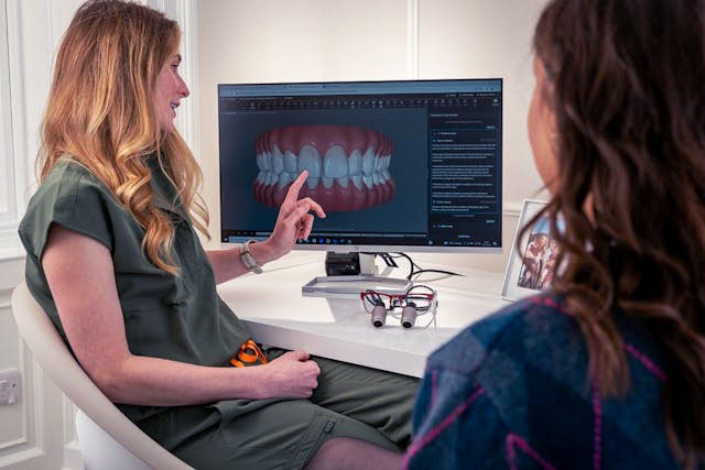 Dentist showing a digital image of a mouth in a computer to a patient.