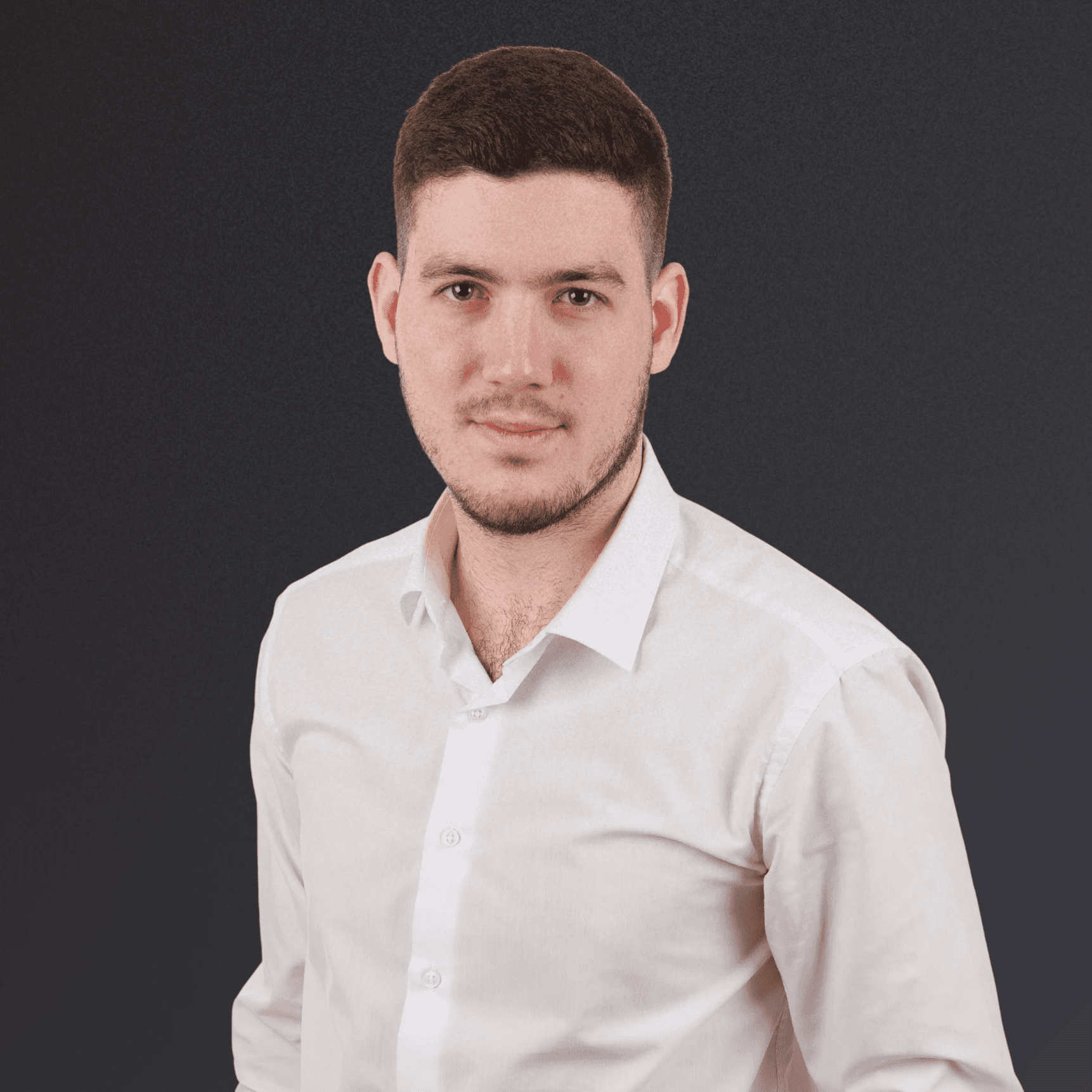 Woman with a short haircut smiling confidently, wearing a blazer and standing in warm natural light with modern architecture behind her.