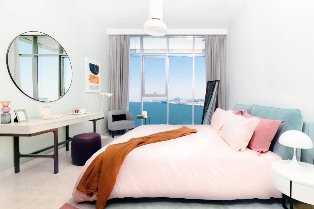 A cozy bedroom with a generous bed and a large mirror, emphasizing modern design at Anwa Omniyat Maritime City
