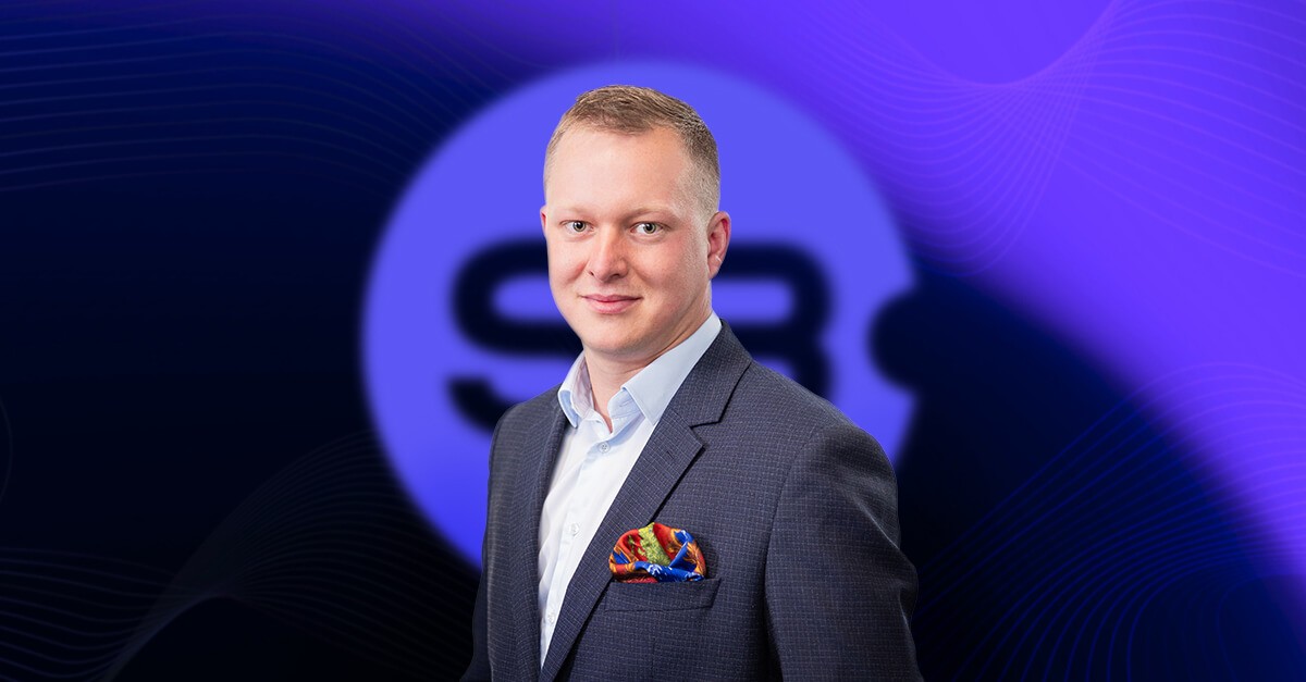 Close-up portrait of Kamil Głowacki, CTO of Sb Software, in a suit jacket with a vibrant pocket square detail.